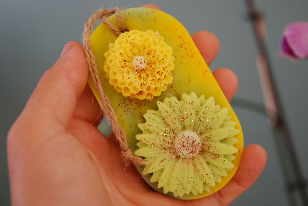 suspension parfumée avec les angles arrondis de couleur jaune et vert pastel ainsi que deux fleurs en cire